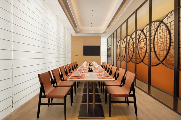 A conference room with a long table, multiple chairs, a flat-screen TV, and a decorative wall with circular patterns. - Hilton Garden Inn Zhengzhou Airport Aerotropolis (Zhengzhou)