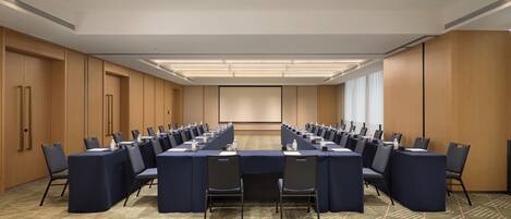 A conference room with a long table, chairs, and a carpeted floor.