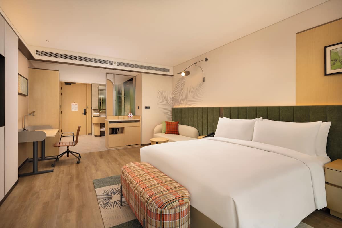A hotel room with a bed, desk, chair, and a small table.