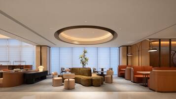 A modern lobby with a central seating area, a reception desk, and a large window providing a view.