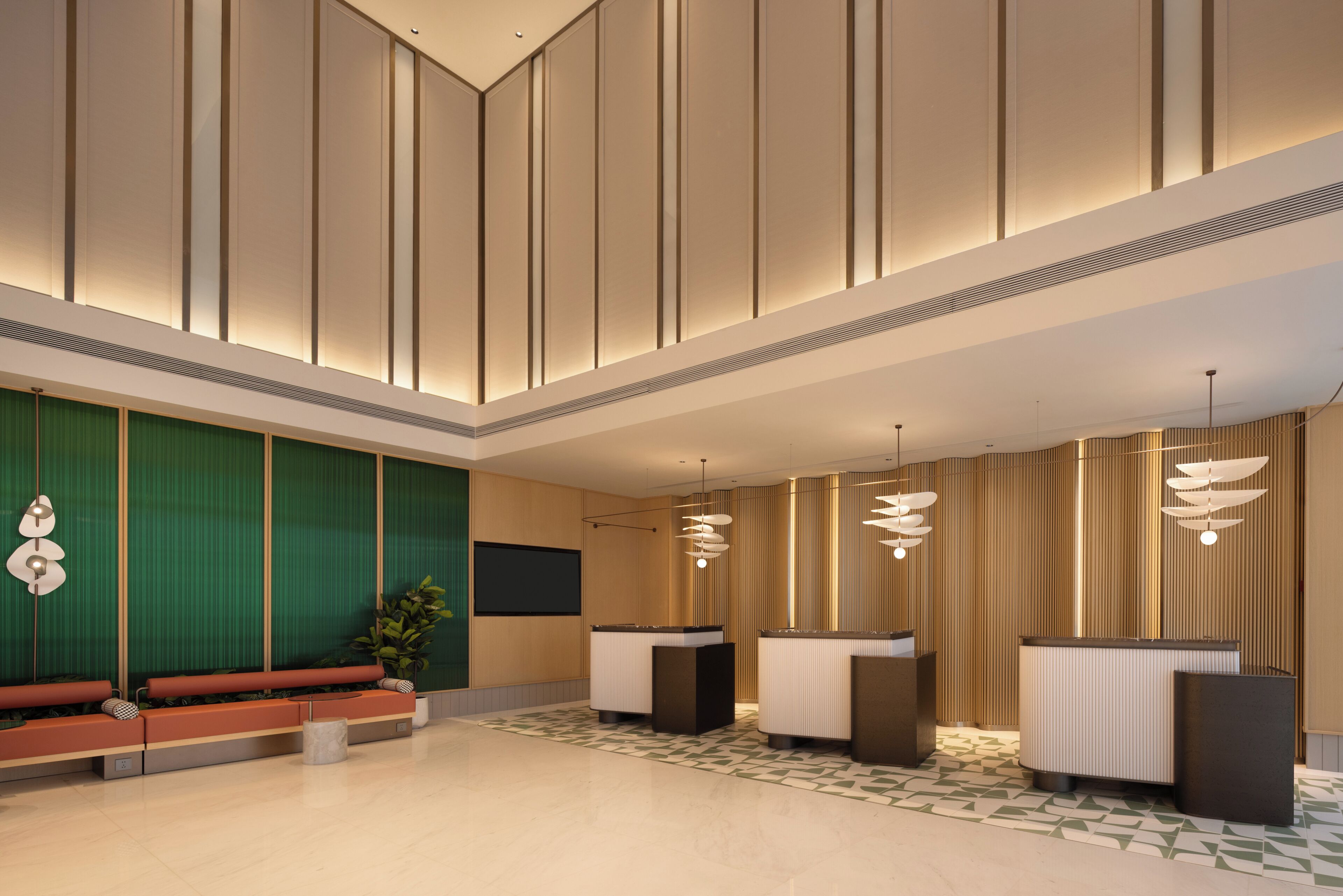 A modern lobby with a high ceiling, a reception desk, seating area, and a large plant.