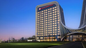 A modern hotel with a prominent Hilton Garden Inn sign, a curved facade, and a well-lit entrance. - Hilton Garden Inn Zhengzhou Airport Aerotropolis (Zhengzhou)