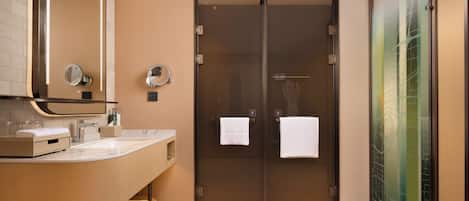 Un baño moderno con un tocador curvo, una cabina de ducha de cristal y un espejo grande.