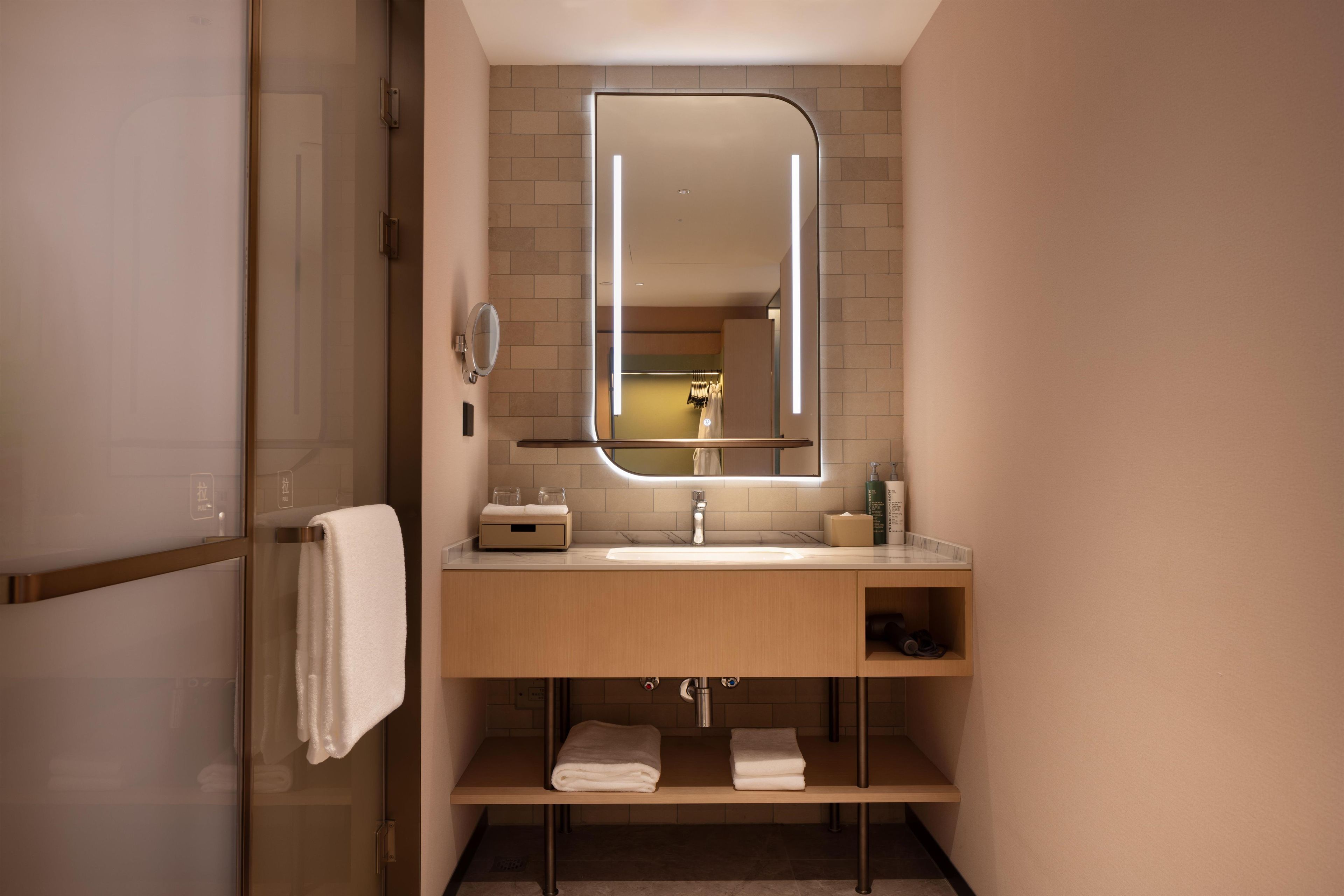 A modern bathroom with a glass shower enclosure, a sink with a mirror above it, and a towel rack.