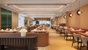 A modern restaurant with a central bar, multiple dining tables, and chairs arranged for guests. - Hilton Garden Inn Zhengzhou Airport Aerotropolis (Zhengzhou)