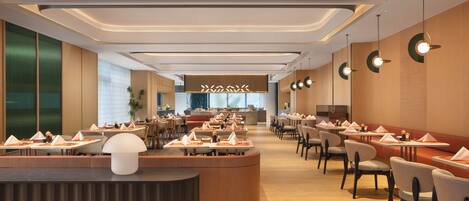 A modern restaurant with a central bar, multiple dining tables, and chairs arranged for guests.