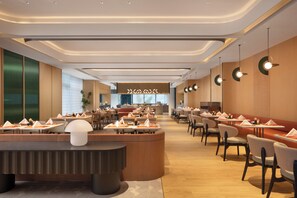 A modern restaurant with a central bar, multiple dining tables, and chairs arranged for guests. - Hilton Garden Inn Zhengzhou Airport Aerotropolis (Zhengzhou)