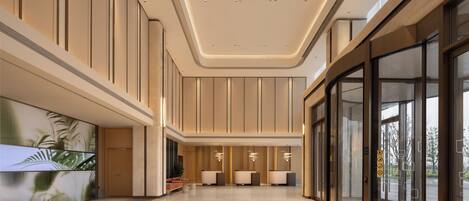 Un vestíbulo amplio con techo alto, mostrador de recepción y puerta de cristal grande.