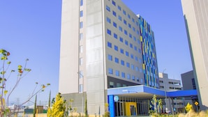 Ein modernes Hotelgebäude mit einem gut sichtbaren 'tru by Hilton'-Schild, mehreren Stockwerken und einem überdachten Eingangsbereich.