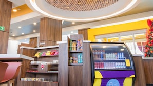 Ein modernes Interieur mit einer Verkaufsmaschine, Regalen voller Snacks und einer runden Deckenleuchte.