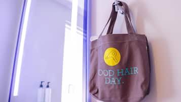 Uma sacola de tecido castanho com um logotipo amarelo e a frase 'GOOD HAIR DAY' pendurada na parede.