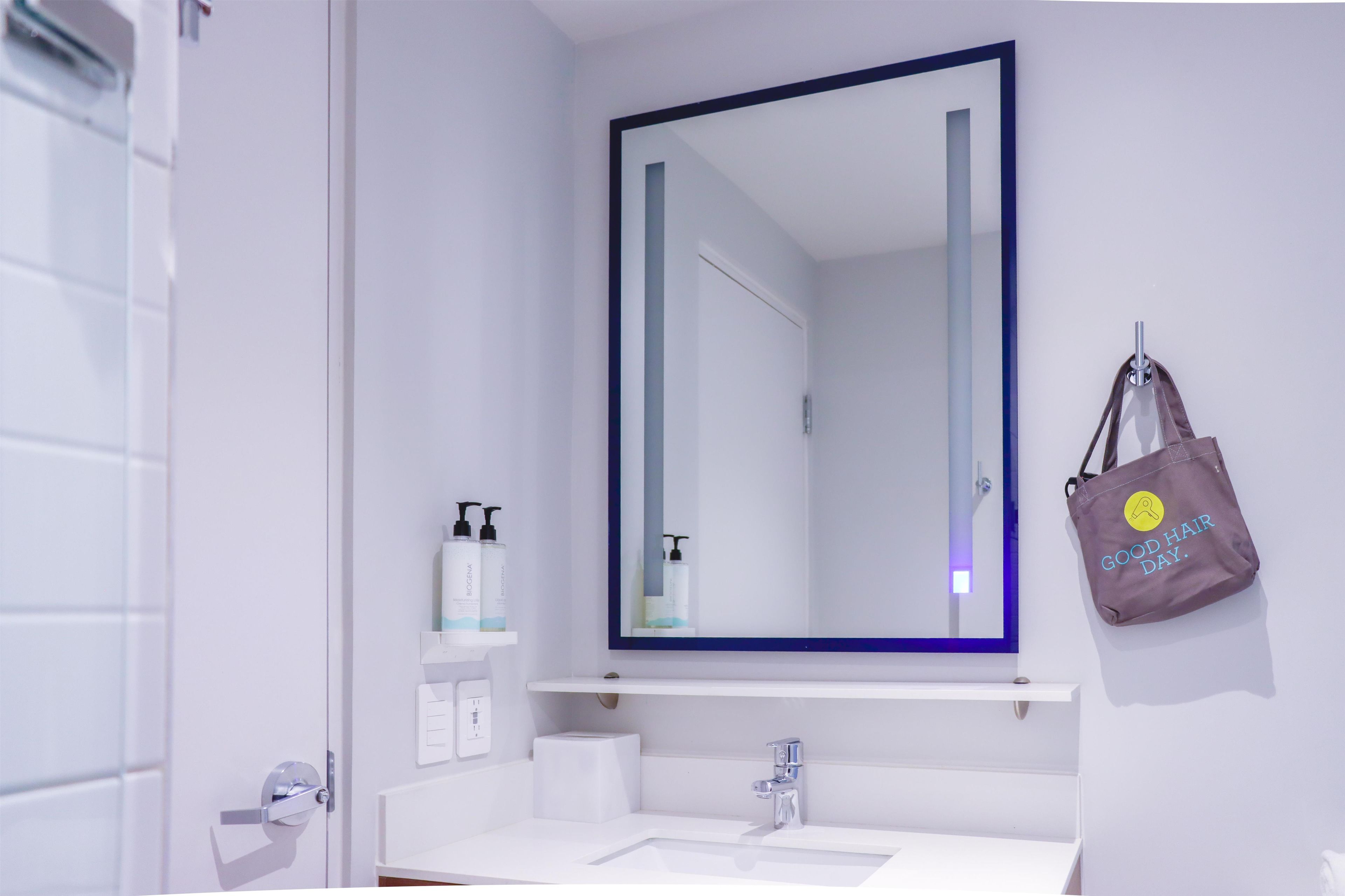 A bathroom with a white sink, a mirror, and a towel hanging on the wall.