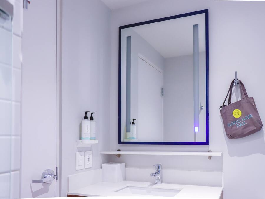 Une salle de bain avec un lavabo blanc, un miroir et une serviette accrochée au mur.