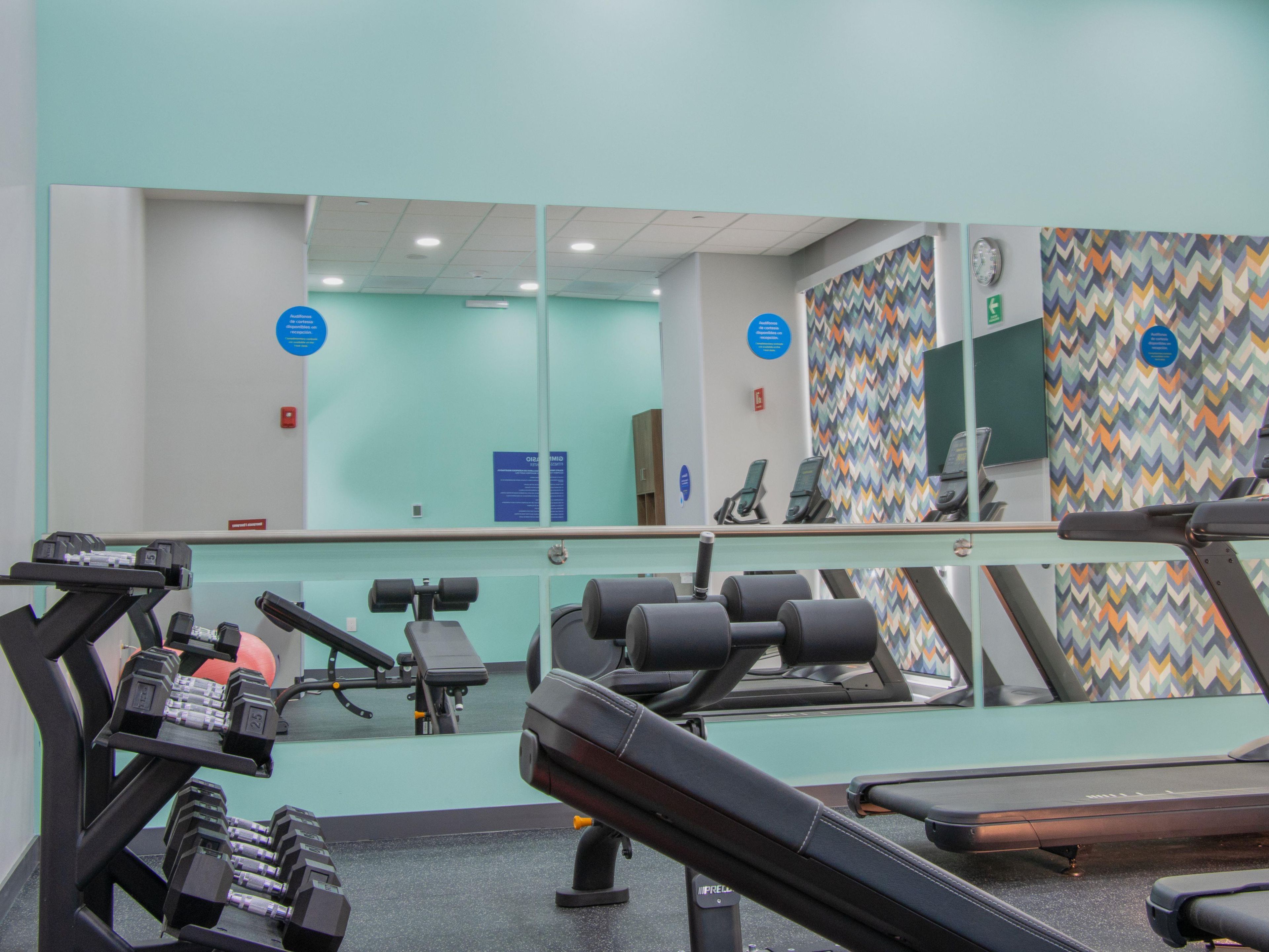 A gym with exercise equipment, a mirror, and a wall with a zigzag pattern.