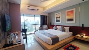 Habitación de hotel moderna con una cama grande, un escritorio con cafetera, televisión y balcón con vistas.