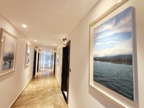 A hallway with framed artwork on the walls, a polished marble floor, and doors leading to rooms. - The Peace Palace Luxury Hotel  (Sunamganj)