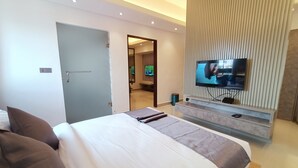 Una habitación de hotel moderna con una cama grande, un televisor montado en la pared y una puerta que da a un baño.