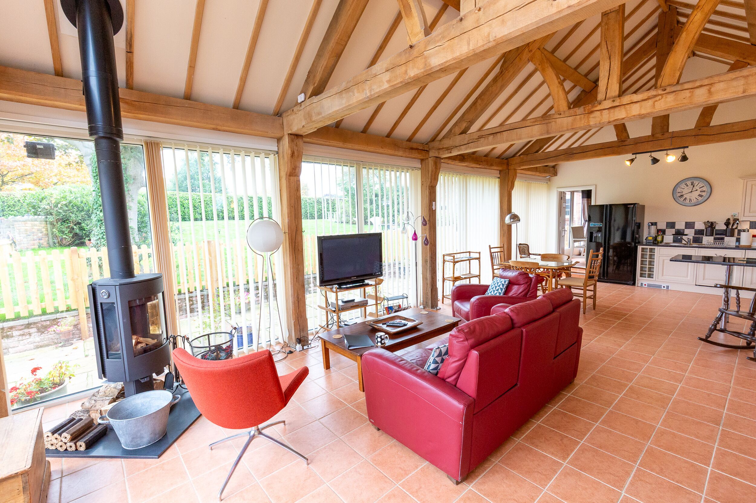 A spacious living area with a red sofa, a television, and a wood-burning stove.