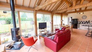 A spacious living area with a red sofa, a television, and a wood-burning stove. - Nature's Lodge (Kidderminster)