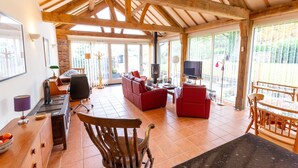 A spacious living area with a fireplace, red sofas, and a wooden dining table. - Nature's Lodge (Kidderminster)