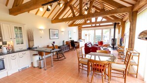 A spacious kitchen with white cabinetry, a dining area with wooden chairs, and a large window providing natural light. - Nature's Lodge (Kidderminster)