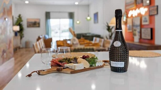A table with a bottle of wine, a cheese board, and glasses in a modern living room with a sofa and artwork on the walls. - Family-Friendly Southside Game House (Chattanooga)