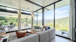 Ein modernes Wohnzimmer mit einer großen Couch, einem Essbereich und Blick ins Freie.