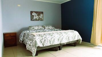 Une chambre à coucher avec un lit, une table de chevet, un tableau accroché au mur et un mur bleu.
