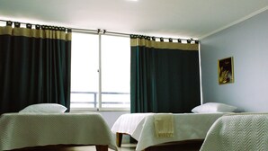 Ein Zimmer mit zwei Betten, einem fensterbelaubten Fenster und einem Wandbild.