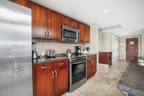 A modern kitchen with wooden cabinets, stainless steel appliances, and a tiled backsplash.