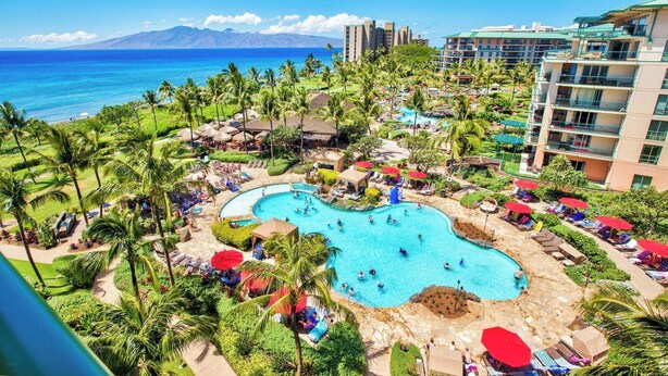 Ein Resort mit einem großen Pool, Palmen und Blick auf den Ozean.