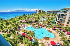 Un resort con una piscina grande, palmeras y vistas al océano.