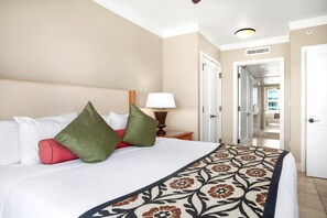 Habitación de hotel con una cama grande, una mesita de noche con lámpara y vistas al pasillo.