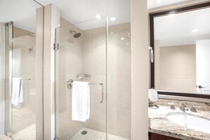 Un baño moderno con ducha de vidrio, tocador con lavamanos y un espejo grande.