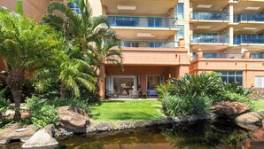 Un hotel con piscina, palme e un giardino curato.