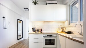 A modern kitchen with white cabinets, a built-in oven, and a window. - Cozy 2BR Near Metro Acropolis View (Athens)