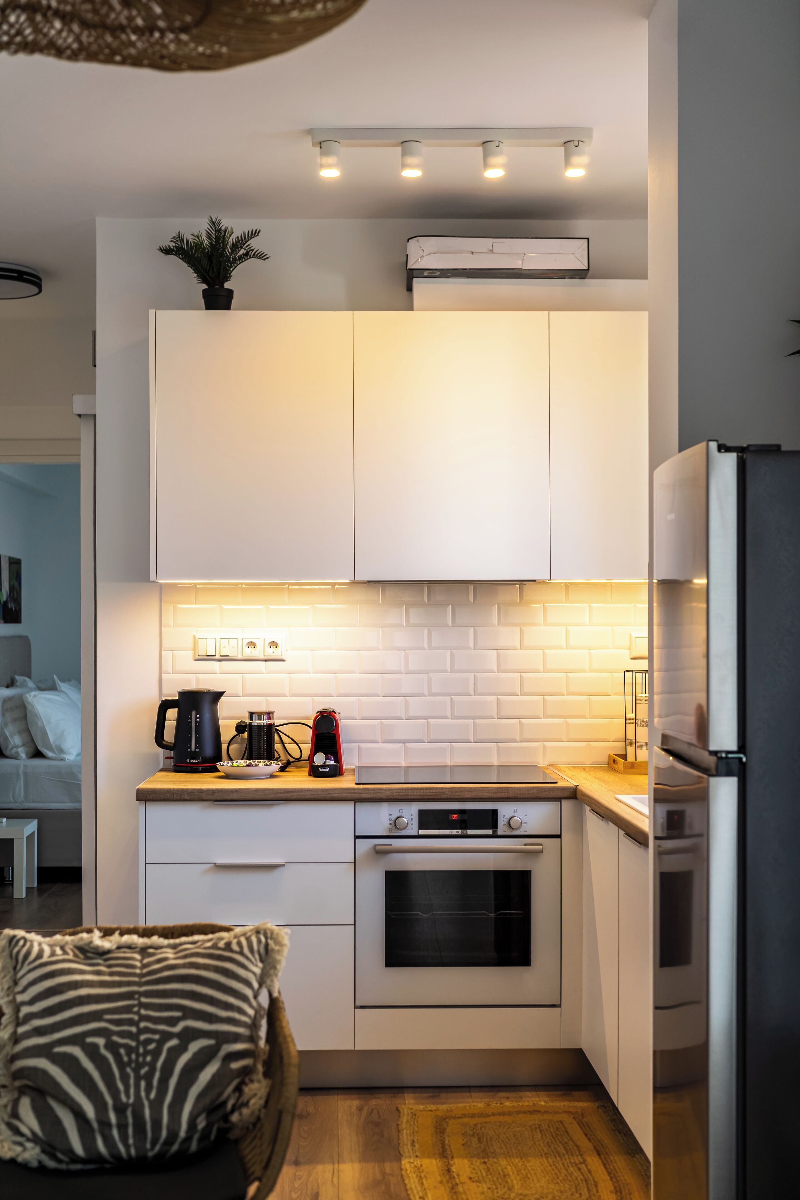 A compact kitchen with white cabinets, a built-in oven, and a refrigerator.