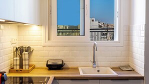 A kitchen with white subway tiles, a window with a view of buildings, a sink, and a countertop with a knife block and a toaster. - Cozy 2BR Near Metro Acropolis View (Athens)