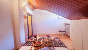 A cozy attic room with a wooden ceiling, a small table with a tray of food, and a chair. - Residenza Marmarole by Ca-Sa Check (Pieve di Cadore)