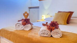 A neatly made bed with rolled towels and decorative flowers, a bedside table with a lamp, and a nightstand with a lamp. - Residenza Marmarole by Ca-Sa Check (Pieve di Cadore)
