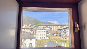 A window view of a town with buildings, a mountain, and a clear sky. - Residenza Marmarole by Ca-Sa Check (Pieve di Cadore)