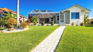 A modern two-story house with a covered patio, a well-maintained lawn, and a clear blue sky.