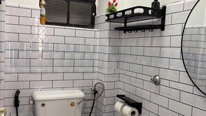 Ein Badezimmer mit weißen Fliesen, einer Toilette, einem Waschbecken und einem Fenster mit schwarzem Rahmen.
