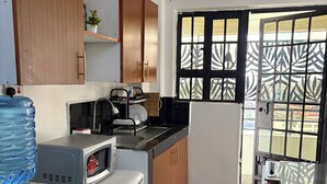 Eine kleine Küche mit Kühlschrank, Mikrowelle, Wasserspender und Spüle.