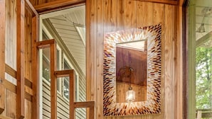 A wooden staircase with a handrail, leading to a room with a large window and a decorative mirror.