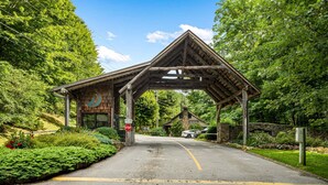 A rustic wooden archway leading to a building with a stone wall and a sign that reads "Woods Rel."