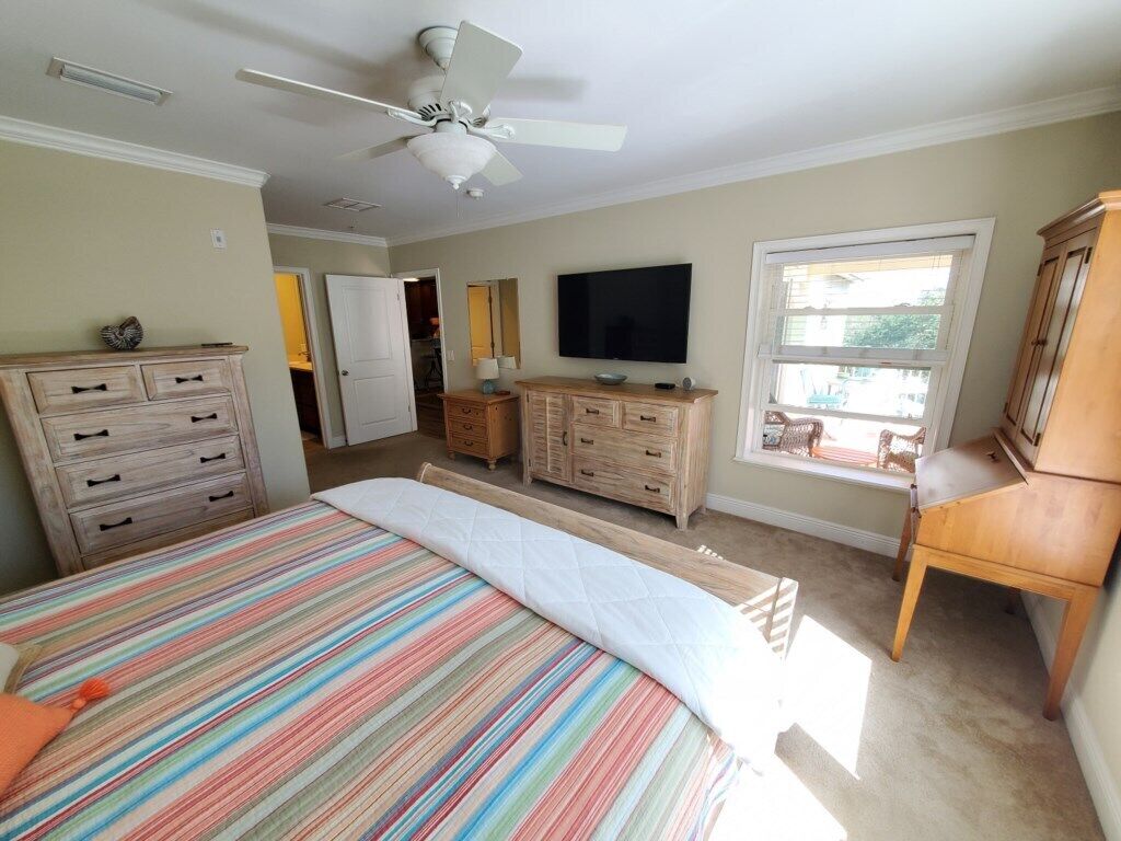 Ein Schlafzimmer mit Bett, Kommode, Fernseher und Fenster.