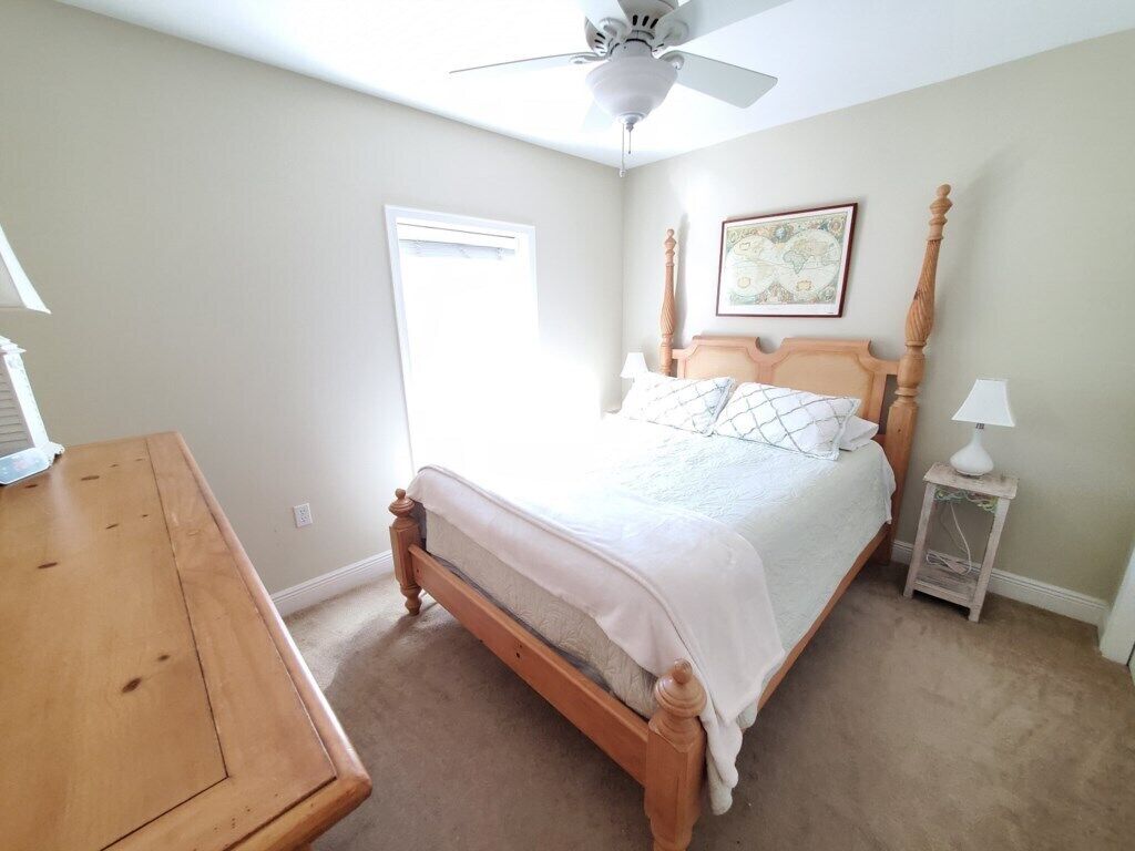 Ein Schlafzimmer mit einem hölzernen Bett, einem Deckenventilator, einem Nachttisch und einem Beistelltisch.