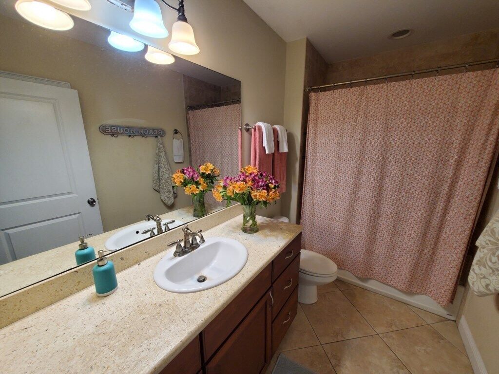 Une salle de bain avec un lavabo, un miroir et un rideau de douche.