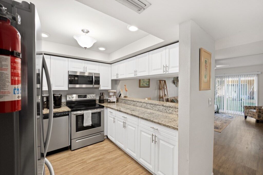 A modern kitchen with white cabinets, stainless steel appliances, and a granite countertop.